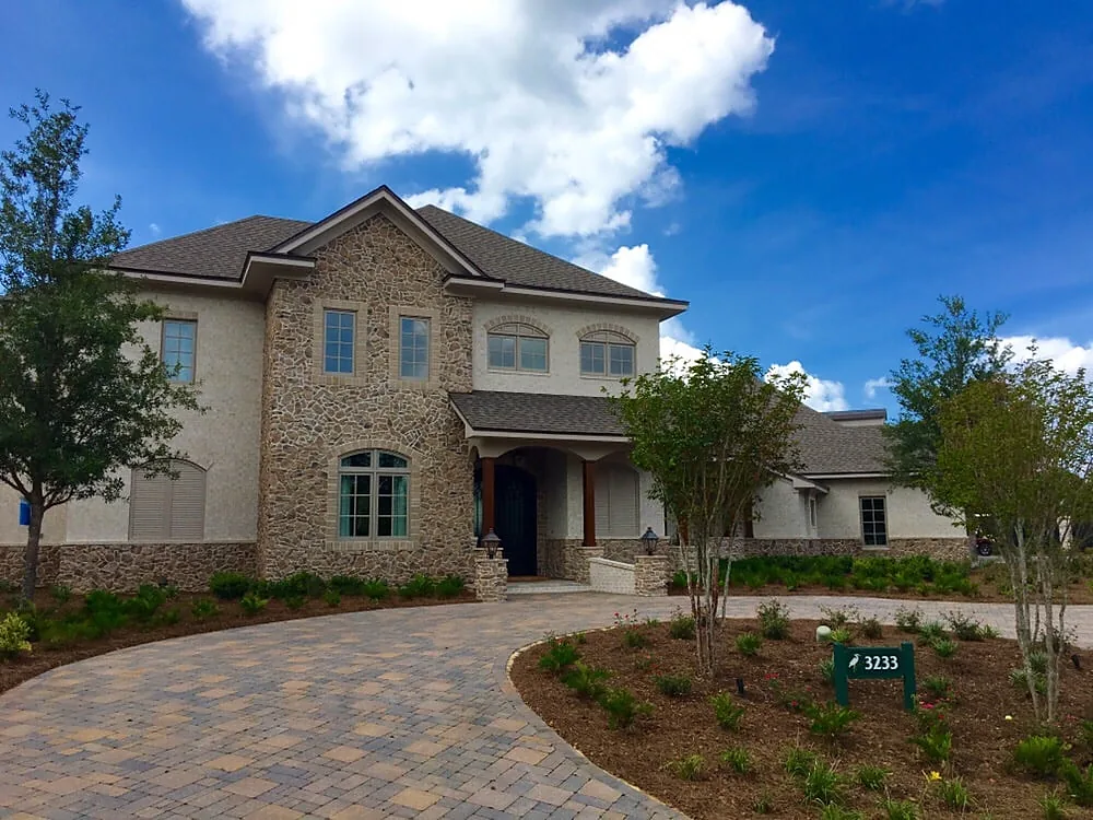 A paver drive and entry apron in front of a two-story brick and stucco house, laid up to the step at the front door